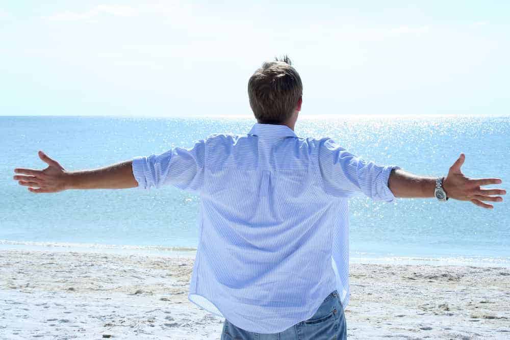 Bedeutung der Zahlen - Lebenszahlen Einführung - Lebenszahl 1 - Mann mit offenen Armen am Strand Meer