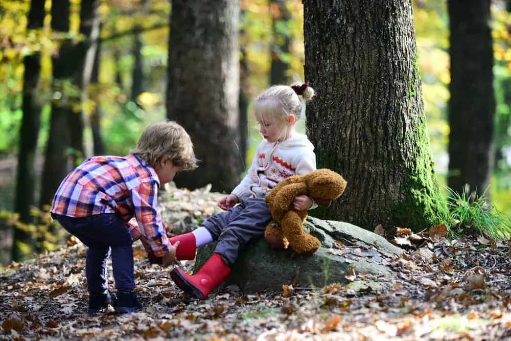 Lebenszahl 6 Kinder: 2 Kinder am Schuhe anziehen im Wald